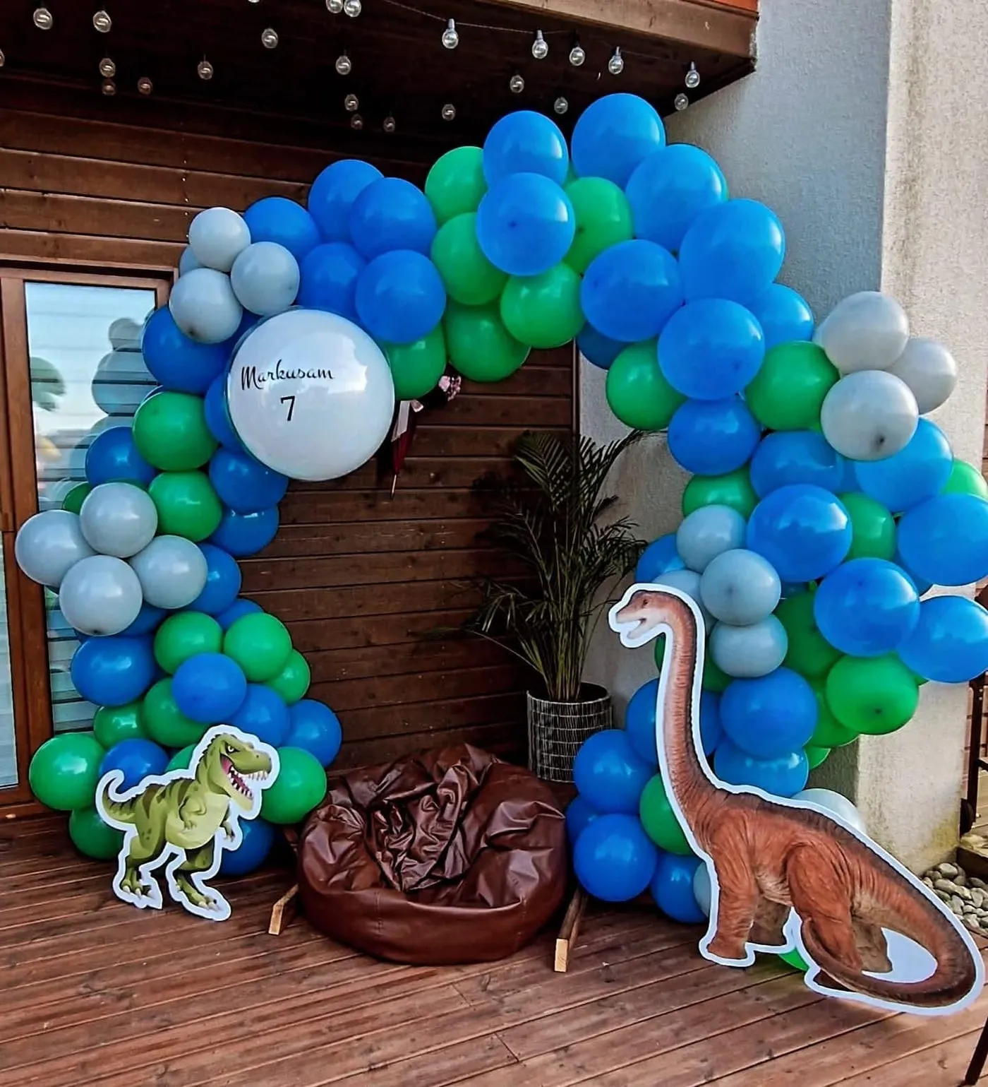 Zila un zaļa balonu arka ar dinozauru figūrām