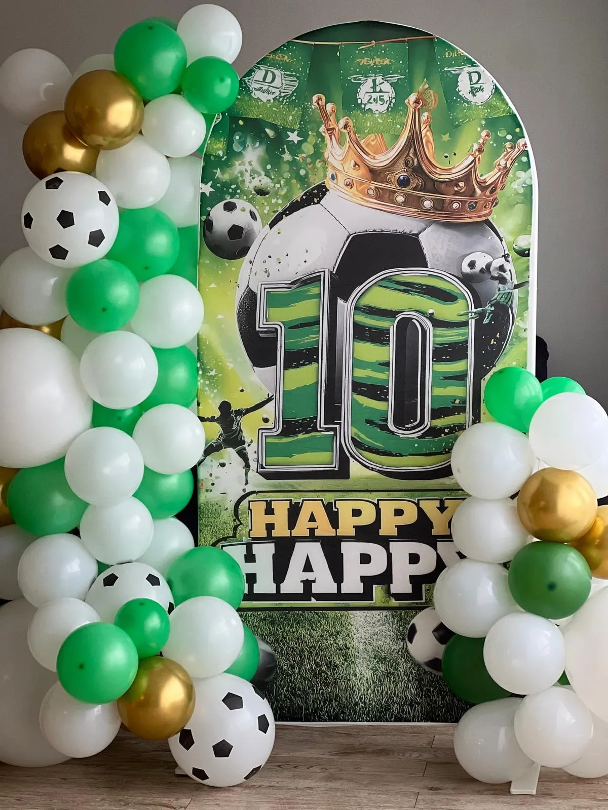 Zaļa, balta un zelta balonu virtene ar futbola tēmas foto sienu BamBalle telpā
