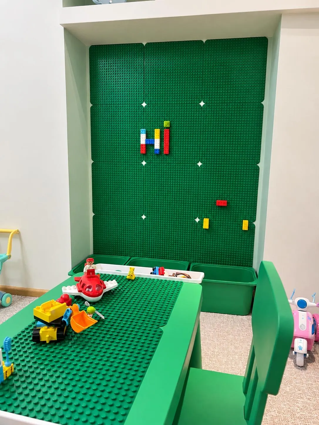 Zaļa LEGO klucīšu siena ar būvēšanas galdu, soliņu un klucīšu kastēm